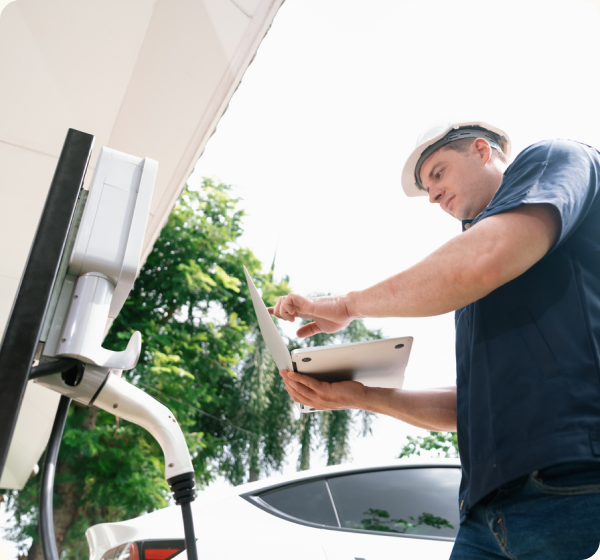 A mom in her garage taking groceries out of the back of her EV while her son plugs the charger in