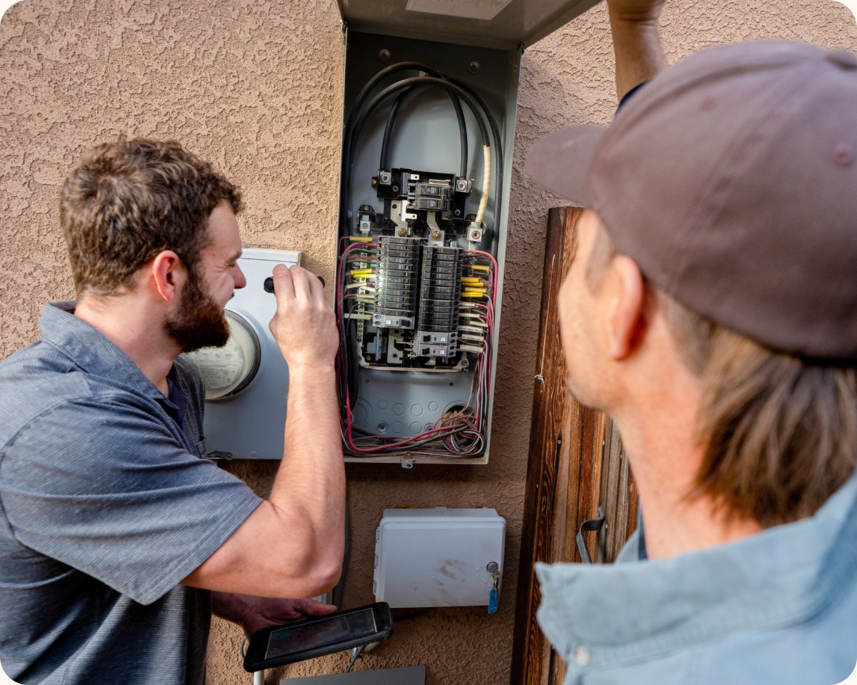 Electricians inspecting a residential electrical panel